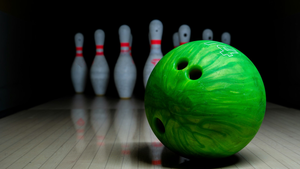 Une boule de bowling est plac&eacute;e devant des quilles sur une piste. 